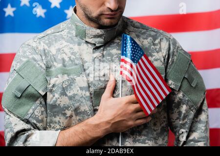 cropped view of patriotic military man in uniform holding small american flag on blurred background Stock Photo