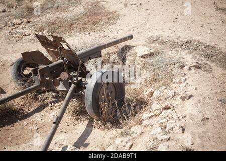 Old rusty cannon from WWII period stands in a sand trench Stock Photo