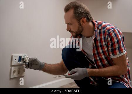 Young caucasian electrical engineer installing power sockets Stock Photo