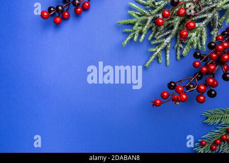 Christmas holidays composition with christmas decorations, red berries and thuja branches on blue background with copy space, top view Stock Photo