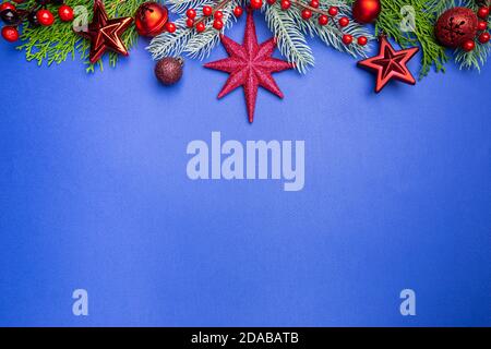 Christmas holidays composition with christmas decorations, red berries and thuja branches on blue background with copy space, top view Stock Photo