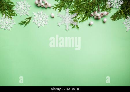 Christmas composition made of snowflakes and thuja branches on green background, top view. Winter concept. Flat lay. Stock Photo