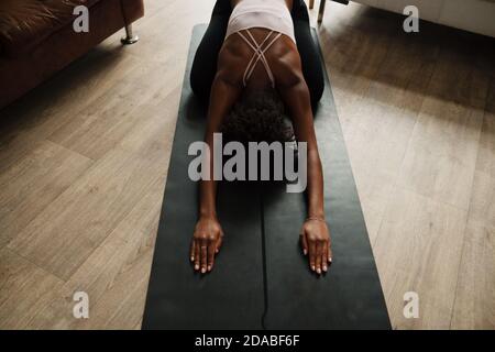 Mixed race woman practising yoga and breathing techniques stretching at home, fitness concept, top down shot Stock Photo