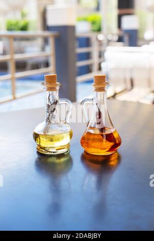 On the table are two glass bottles filled with spicy and rosemary olive oil. Close-up. Butter for pizza, rest in an Italian restaurant Stock Photo