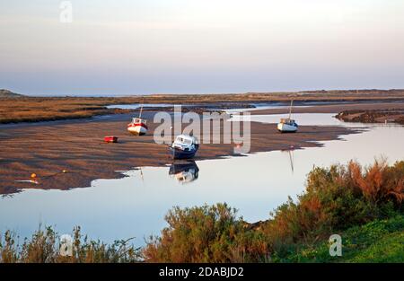 A view of boats beached at low water in Overy Creek on the North Norfolk coast at Burnham Overy Staithe, Norfolk, England, United Kingdom. Stock Photo