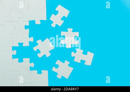 A unfinished puzzle with pieces on a light blue background Stock Photo