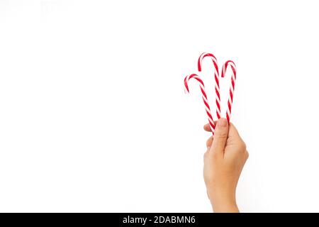 Woman hand holding three candy canes on a white background and with copy space Stock Photo