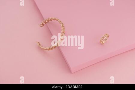 Chain shape Golden ring and bracelet on pink color background Stock Photo