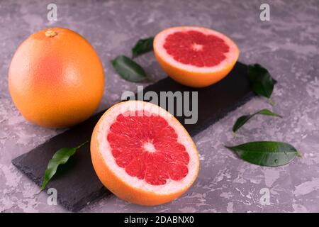 Grapefruit and grapefruit wedges on a gray background. Close-up. Stock Photo