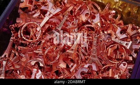 Paris, France - 09/08/2019: Closeup view of metal miniatures of Eiffel Tower with pink color sold to tourists as key fob souvenir in s gift shop. Stock Photo