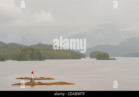 Scenic view from the ferry to the Inside Passage off Vancouver Island. In foreground a rock with a beacon. In background wooded islands and mountains. Stock Photo