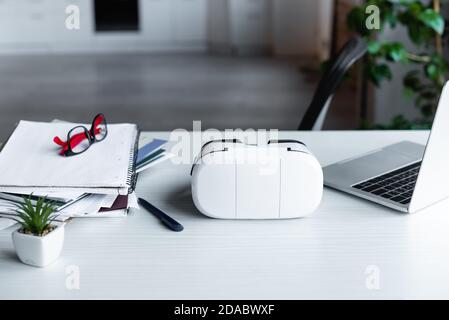 vr headset, laptop, notebooks and eyeglasses on table Stock Photo