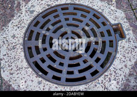Abstract circle iron metal drain lid or round manhole drain cover texture on concrete pavement floor, top view. High quality photo Stock Photo