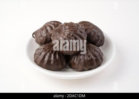 Chocolate-covered marshmallows on a white plate. Side view. Stock Photo