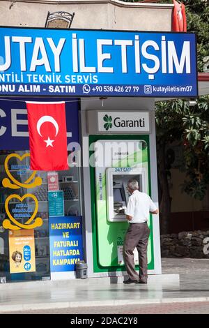 Antalya, Turkey-circa Oct, 2020: Turkish senior man uses ATM of the Garanti BBVA. The Garanti Bank is the second largest private bank in Turkey Stock Photo