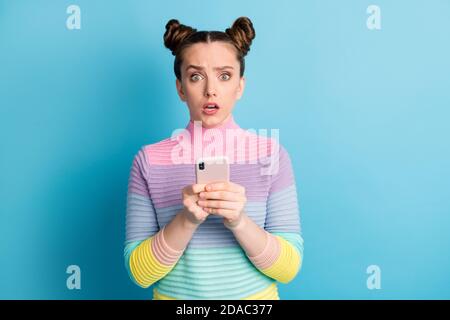 Photo of pretty amazed shocked teen lady two nice buns influencer freelancer hold telephone read followers comments bad mood wear striped sweater Stock Photo