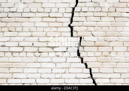 a large long and wide crack in a white brick wall Stock Photo