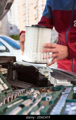 Driver hands inserting air cartridge inside airbox of car engine, close-up view Stock Photo