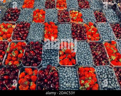Fruits beautiful diagonal layout background in plastic boxes baskets , top view of summer organic food - strawberries, blueberries, sweet cherries at Stock Photo