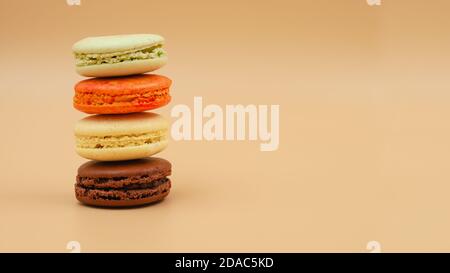 Four brightly colored stacked up French Macarons on peach background Stock Photo