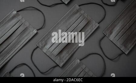 Black medical face mask pattern. Protective face disposable surgical masks on black background cover mouth nose. Prevent covid 19, Coronavirus Stock Photo