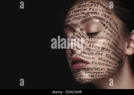 Portrait of beautiful woman with painted words on her face. Art make-up. Stock Photo