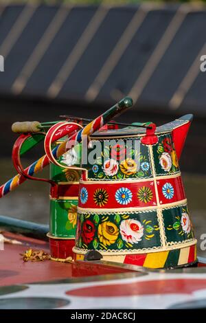 two decorative roses and castles canal wear watering cans or buckets on the top of a traditional narrow boat painted in bright heritage colours. Stock Photo