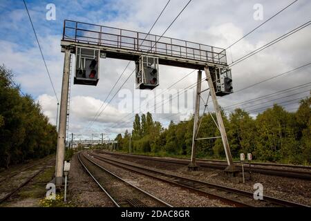 A row of overhead and gantry railway signals that control the movement of trains On UK electrified railway Stock Photo