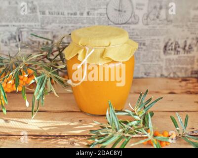 Glass jar with sea buckthorn syrup on the rustic wooden table Stock Photo