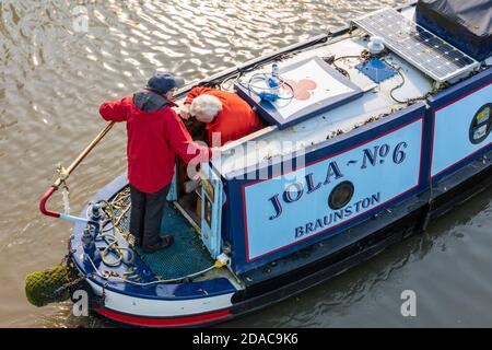 an older man steering a narrow boat on the grand union canal at braunston near daventry, northamptonshire, uk Stock Photo