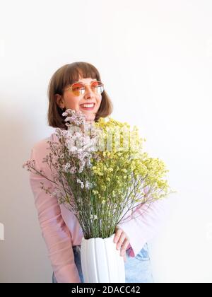 Young woman in pink shirt with vase of flowers Stock Photo