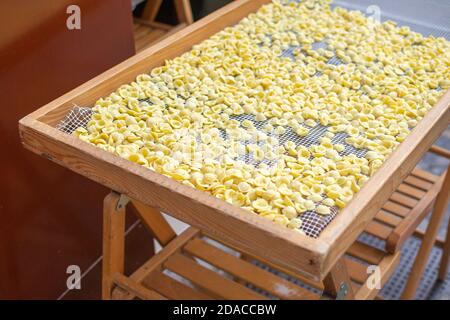 Fresh home made Italian Orecchiette pasta on a wooden table on the street in the Apulia (Puglia) region Stock Photo