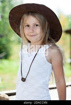 Portrait of preschool girl dressed sleeveless sports shirt and brown cowboy hat at summer season, one child Stock Photo