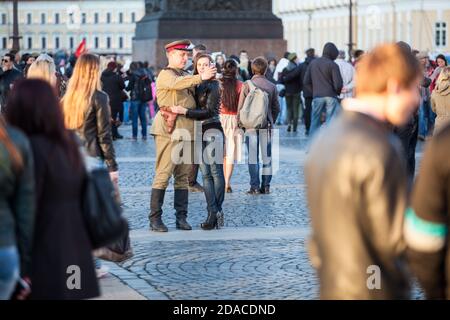SAINT-PETERSBURG, RUSSIA-MAY 9, 2015: Man dressed soviet uniform makes selfie with young woman in center of the Palace Square. Celebration of the 70 a Stock Photo