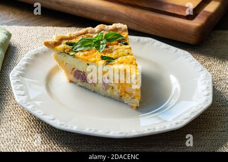 Fresh slice of quiche lorraine on a white plate Stock Photo
