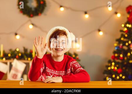 Happy boy smiling and waving hand saying hello during video call or Christmas live stream Stock Photo