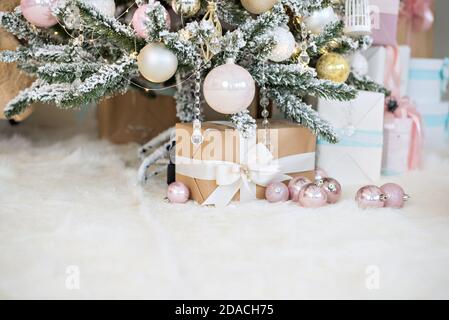New Year greeting card. Craf boxes with gifts from Santa Claus lie on white fur under a snowy Christmas   tree decorated with glass toys, pink balls Stock Photo