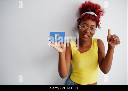 African woman with afro hair, wear yellow singlet and eyeglasses, hold Melilla flag isolated on white background, show thumb up. Stock Photo