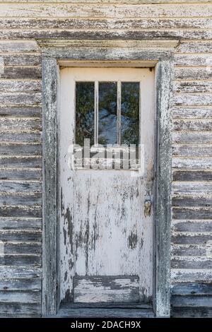 Old weathered white door with peeling paint on the front of abandoned house Stock Photo