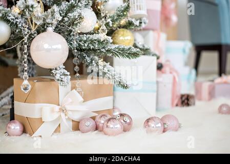 New Year greeting card. Craf boxes with gifts from Santa Claus lie on white fur under a snowy Christmas   tree decorated with glass toys, pink balls Stock Photo