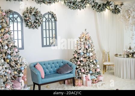 New year greeting card. Elegant interior with snow-covered, fashionable Christmas trees with boxes of gifts, decorated with garlands, wreaths, glass Stock Photo