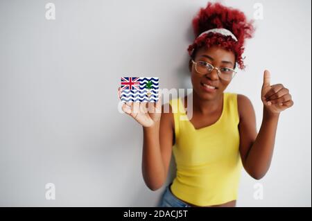 African woman with afro hair, wear yellow singlet and eyeglasses, hold British Indian Ocean Territory flag isolated on white background, show thumb up Stock Photo