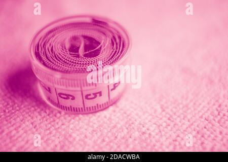 Measuring tape in box on the table. Pink tone. Stock Photo