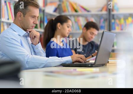 male teacher explaining topic on laptop to student Stock Photo
