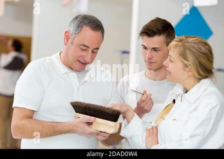 apprentices learning how to paint with a thick brush Stock Photo