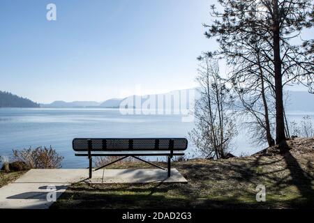 An empty park bench faces Chatcolet Lake at Heyburn State Park in North Idaho. Stock Photo