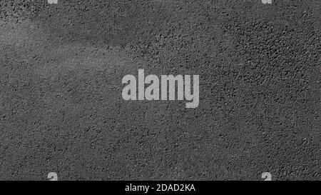 A smooth dark grey asphalt pavement texture with small rocks Stock Photo