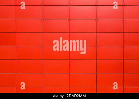 texture of the iron facade of an industrial building made of sheet metal panels with rivets, a close-up of the construction details painted in red wit Stock Photo