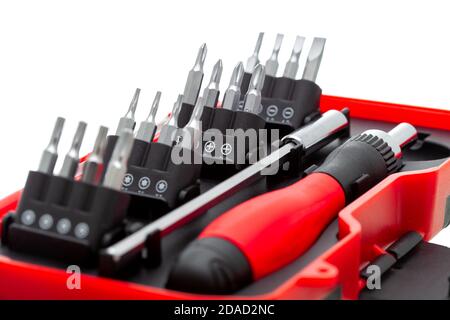 a set of working tools with a screwdriver and bits for repair in an open plastic box with iron nozzles, an object isolated on a white background view. Stock Photo