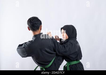Two fighters in pencak silat uniform pose with stances in an outdoor ...